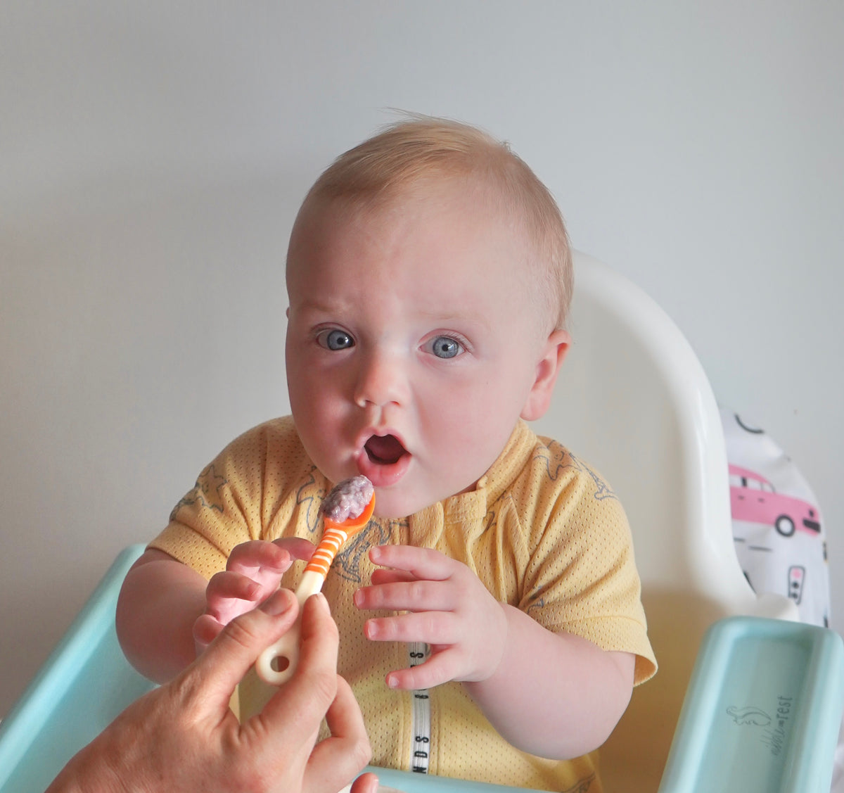 Baby being fed by mother using First Feeding Spoons, orange