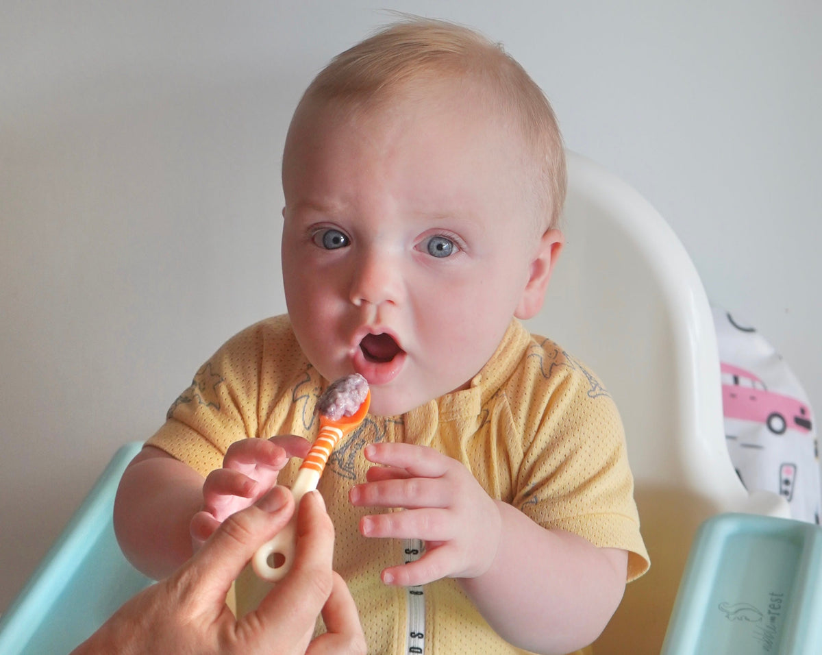 Baby being fed by mother using First Feeding Spoons, orange