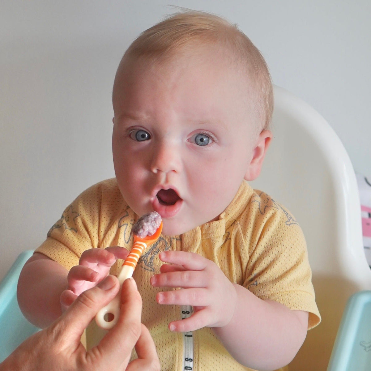 Baby being fed by mother using First Feeding Spoons, orange