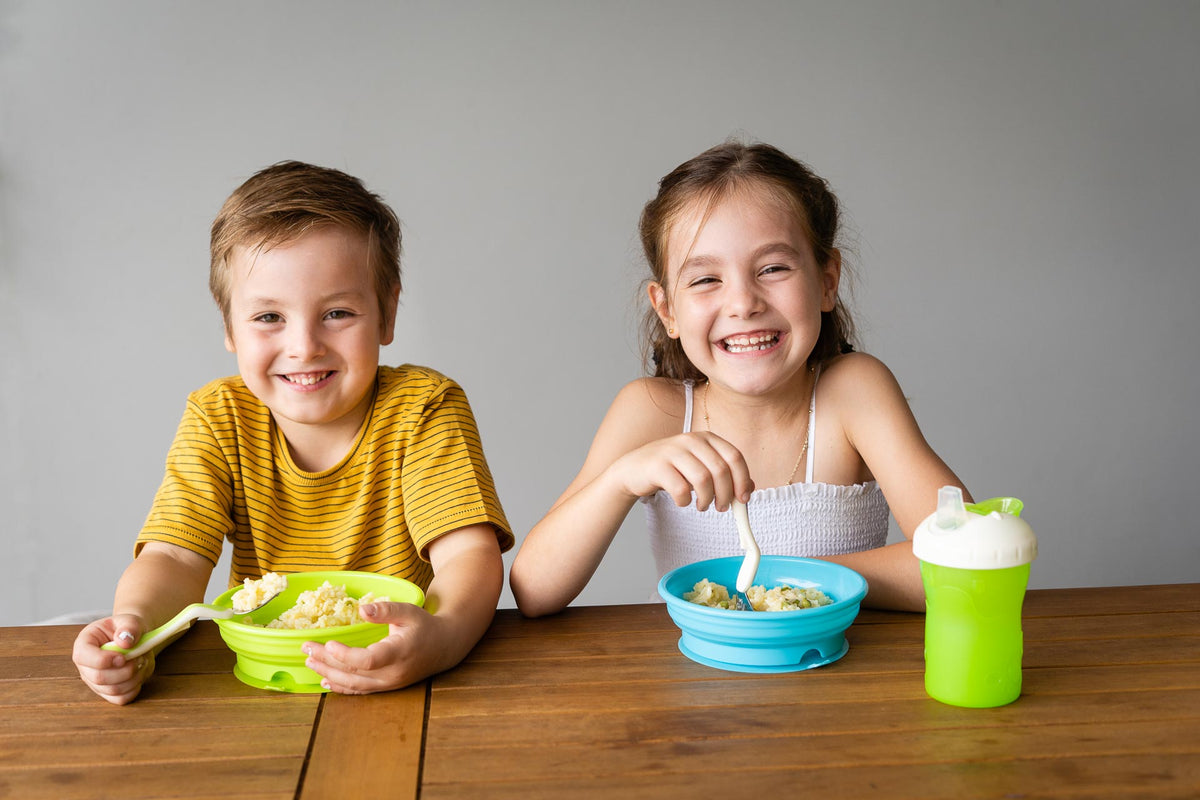 Children smiling, eating from children's bowls, toddler bowl green and purple