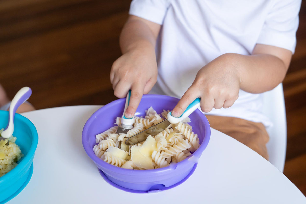 Child using knife and fork set, baby cutlery with purple bowl